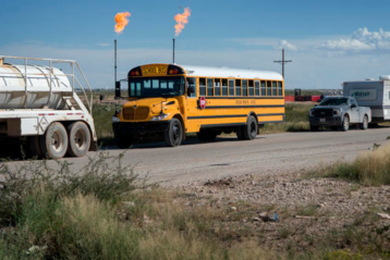 School bus with gas flaring in background