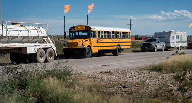 School bus with gas flaring in background